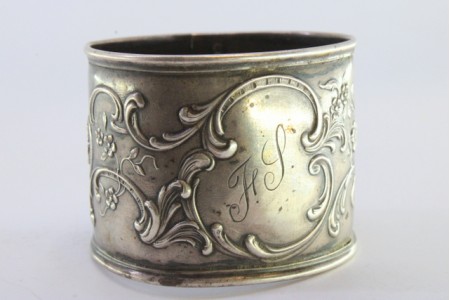 Argola de guardanapo em prata com motivos florais relevados envolvendo cartela para monograma.